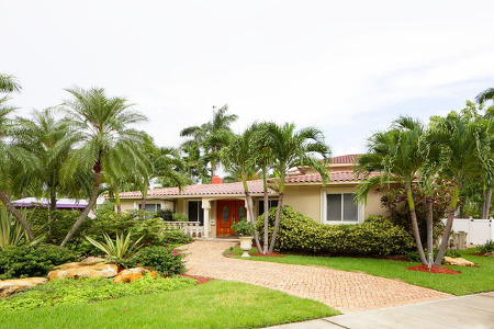 yellow home with clay tile roof & palm trees